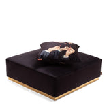 Square black fabric pouf with gold trim at the base, topped with a black cushion featuring a print of hands in elegant gestures against a white background.