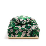 Square modular pouf and matching cushion with green leaves and white rose pattern on fabric upholstery, viewed from front against a white background.