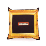 Square black pillow with a thick, ornate golden frame printed around the edges and the word TOILETPAPER centered in bold text on an orange and white background.