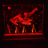 Red LED-illuminated acrylic panel depicting a person being rescued while leaping toward a snowmobile in a snowy night scene with pine trees and a full moon.