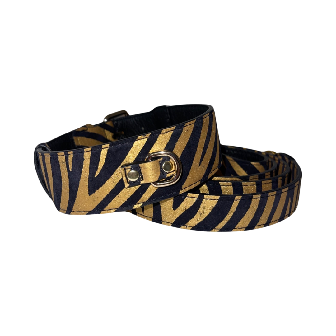 Black and gold zebra print Italian leather dog collar and matching leash set with gold-tone hardware, displayed coiled on a white background.