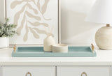Rectangular pale blue decorative tray with gold handles holding two small neutral-toned ceramic containers on a white dresser with brass ring pulls.