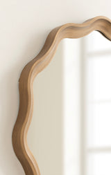 Round mirror with a wooden frame featuring a scalloped, wavy edge and smooth, natural wood grain finish, shown angled against a white wall.