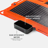 Close-up of black sun efficiency meter and sensor on an orange-framed flexible solar panel with thin parallel solar cells, shown on white background.