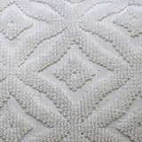 Close-up of a white decorative pillow featuring a raised, textured ogee pattern with diamond shapes on a soft fabric background.