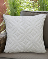 White 18x18-inch decorative pillow with a textured ogee pattern, placed on a gray outdoor wicker chair with green grass in the background.