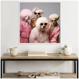 Framed canvas on wall showing four poodles dressed in pink and floral outfits with matching sunglasses, posed against a gray background above a wooden table.