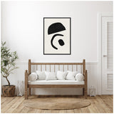 Minimalist living room with a wooden bench, white cushions, and a black and white abstract geometric print framed on the wall above, featuring bold black shapes on a white background.