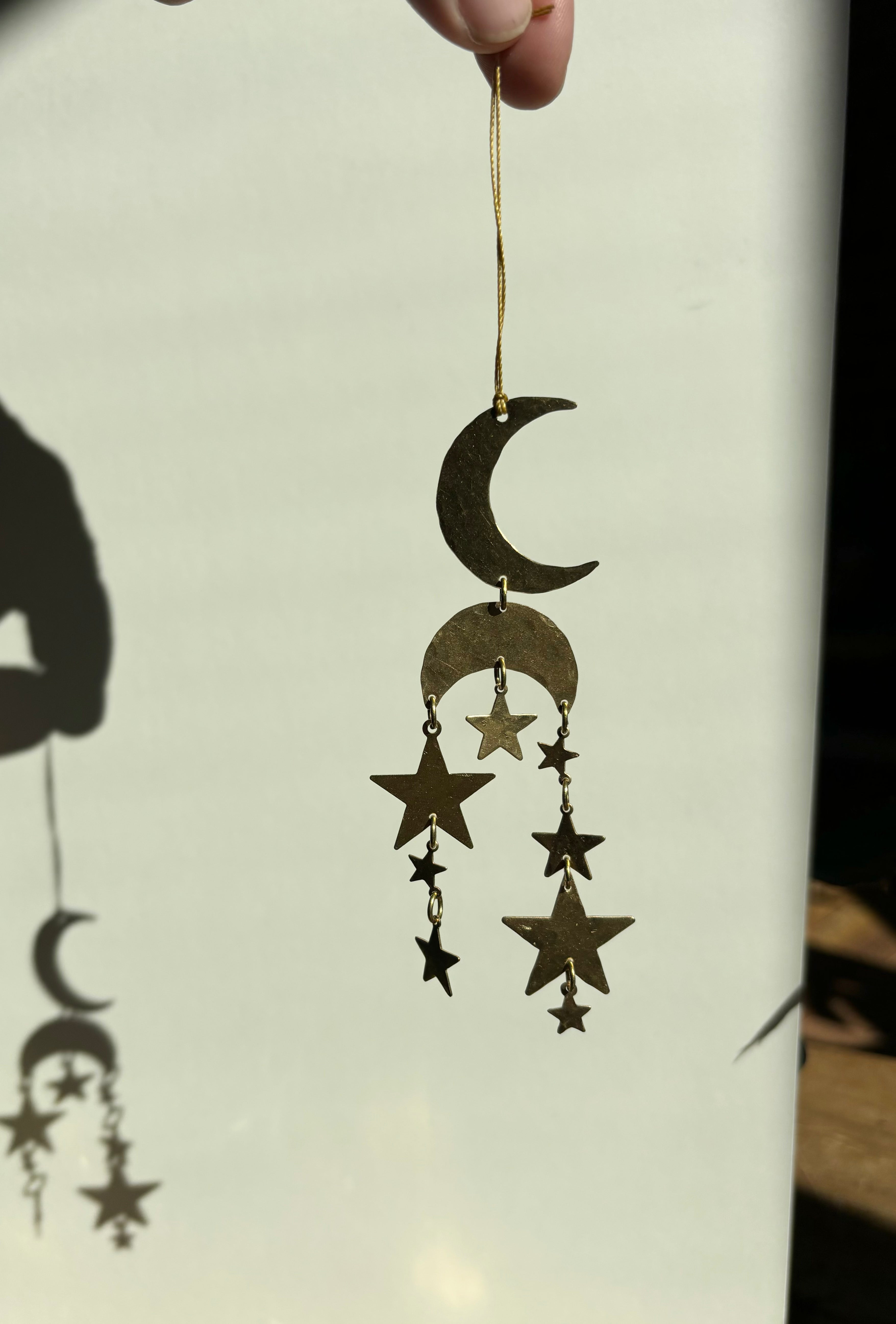 Oh My Stars celestial brass ornament hanging indoors with warm light play