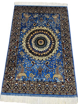 Rectangular hand-knotted Afghan rug in sky blue with a detailed central medallion in cream and black, framed by an intricate dark border and floral motifs.