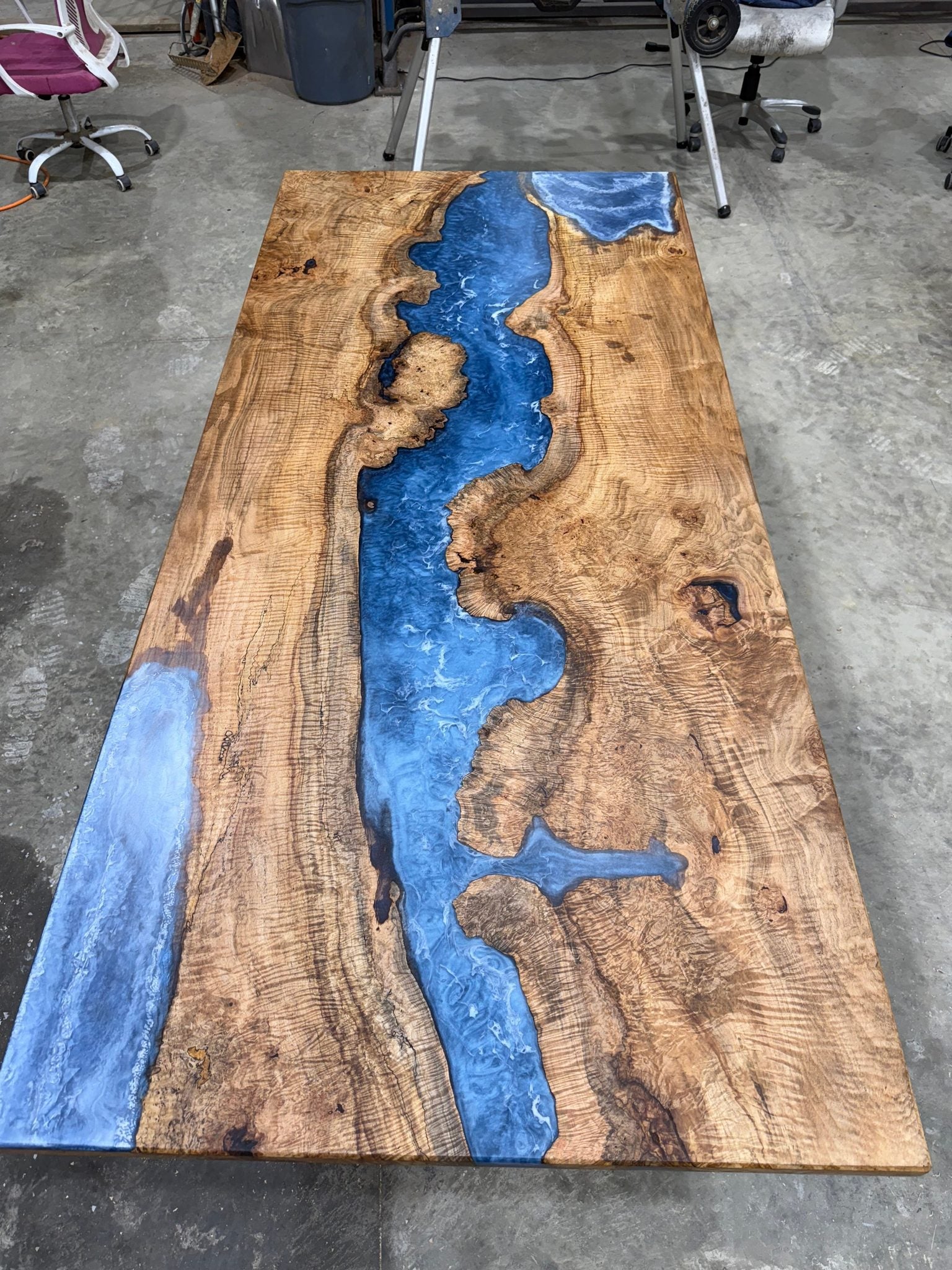 Maple Burl Epoxy River Dining Table with black steel base in a bright dining room