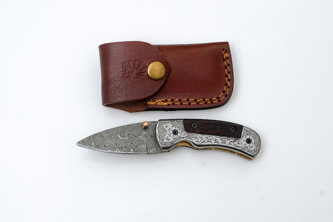 Hand-Forged Damascus Folding Knife with engraved steel bolster, dark wood handle, and detailed spine file work