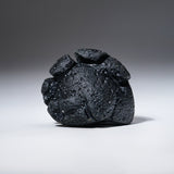 Genuine Indochinite Tektite specimen in display case on black stand