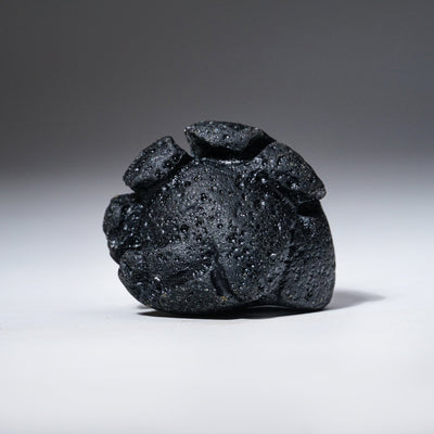 Genuine Indochinite Tektite specimen in display case on black stand