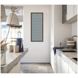 Minimalist kitchen with concrete countertops, white cabinets, large window, and a vertical blue botanical block print with white flower patterns framed on the wall.