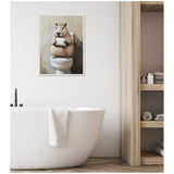 Framed painting of a capybara holding a toilet paper roll while sitting on a toilet, hung on a white wall above a modern white bathtub in a bathroom