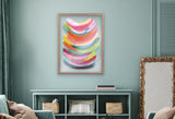 Abstract framed art with bright curved brushstrokes in pink, yellow, blue, and green, hanging above a teal shelving unit with woven baskets and books.