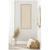 Tall beige pinboard with a delicate green lattice pattern inside a muted green frame hanging on a light gray wall above a woven basket and a white vase with pampas grass.