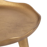 Close-up of a gold-toned metal plant stand featuring a gently scalloped edge and a textured surface finish.
