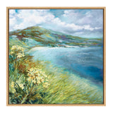 Framed landscape painting of a coastal scene with tall green grasses and yellow flowers in the foreground, rolling green hills in the distance, and a cloudy blue sky above.
