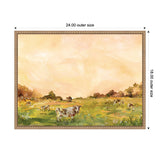 Framed canvas painting showing cows grazing in a green field under a soft orange sky, with trees in the background and flowers in the foreground.