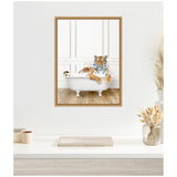 Framed canvas showing a tiger lounging in a vintage white clawfoot bathtub against white paneled walls and wooden floor, mounted on a clean white wall above a desk.
