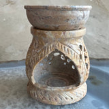 Carved soapstone essential oil burner with intricate leaf patterns and a shallow bowl on top, featuring natural beige and brown stone hues.