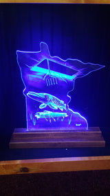 Blue LED-lit acrylic sculpture shaped like Minnesota with a fish and a fishing spear design, mounted on a wooden base.