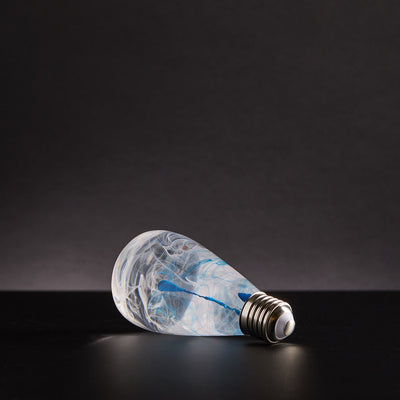 EP Light Blue-Drop Resin LED Bulb handcrafted with eco-friendly resin, shown with wooden base options