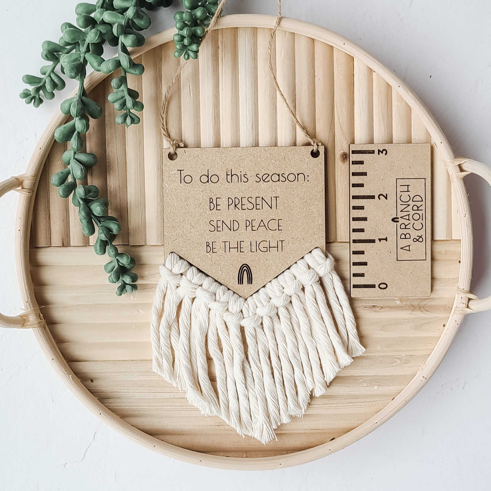 Mini Holiday Hanging Wall Decor with wooden sign, macrame cord, and burlap string hanging on a light wall