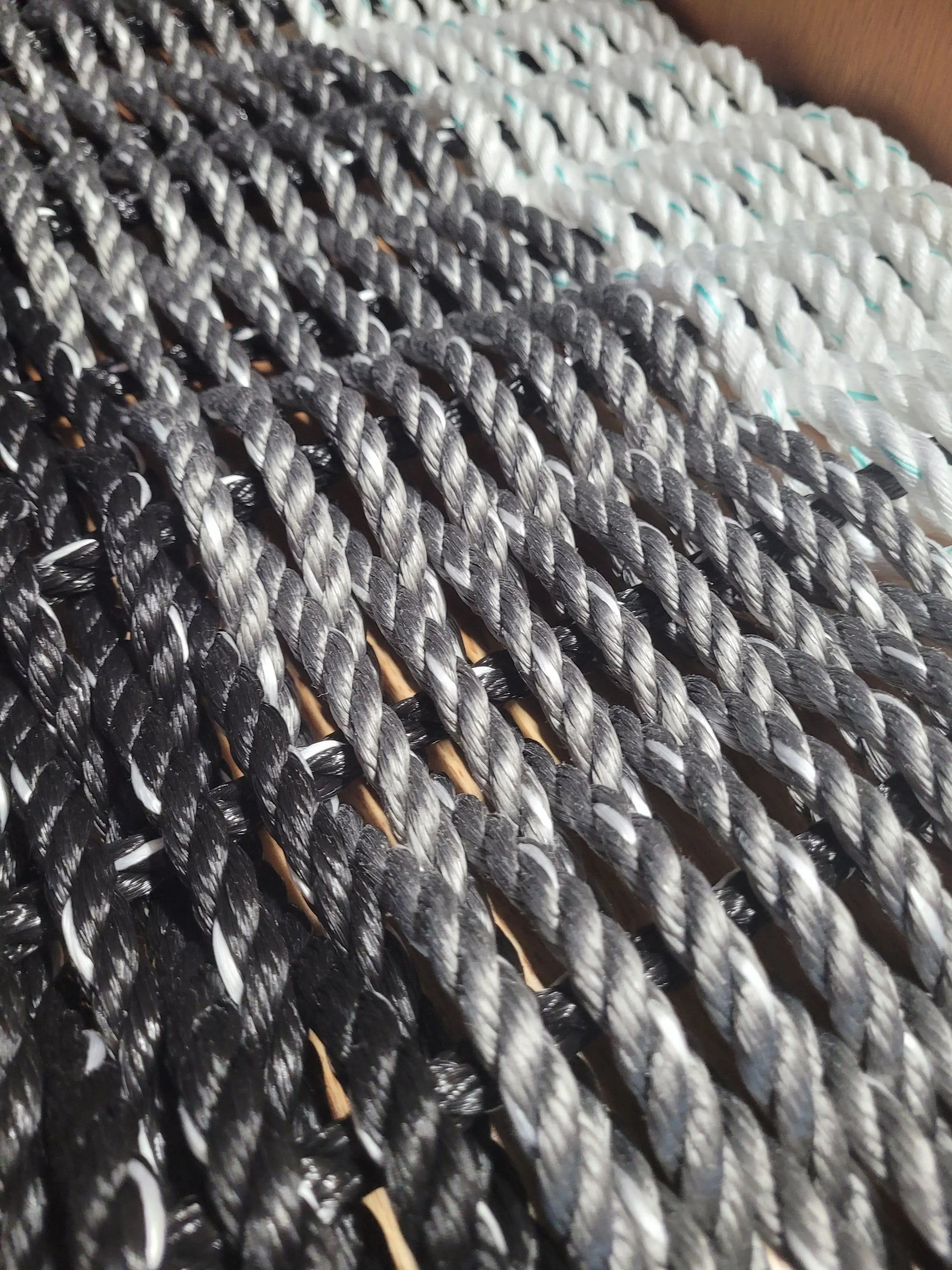 Handmade rope mat made from lobster rope in black, gray, and white colors