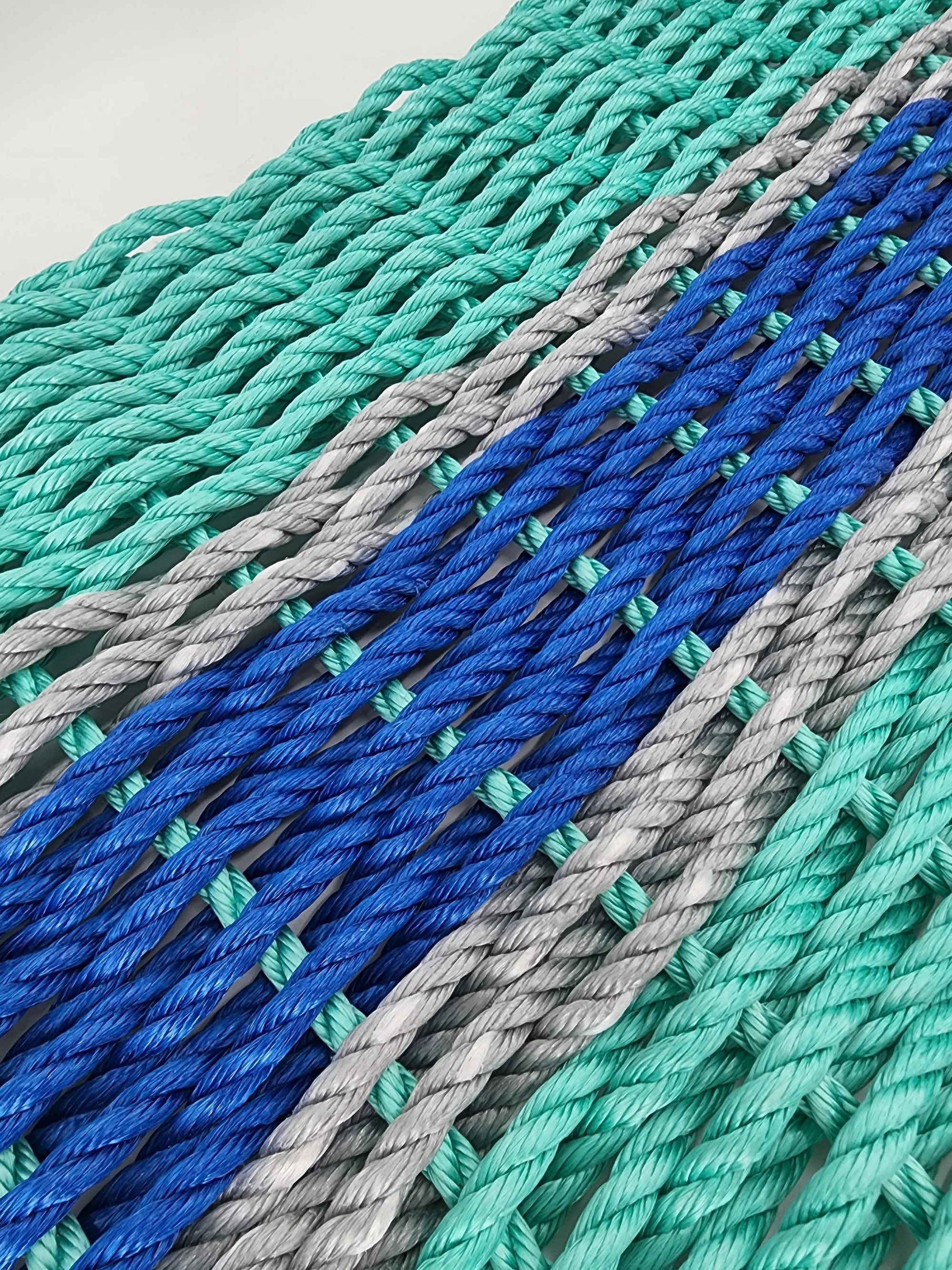 Handmade lobster rope door mat in teal and blue with light gray accents