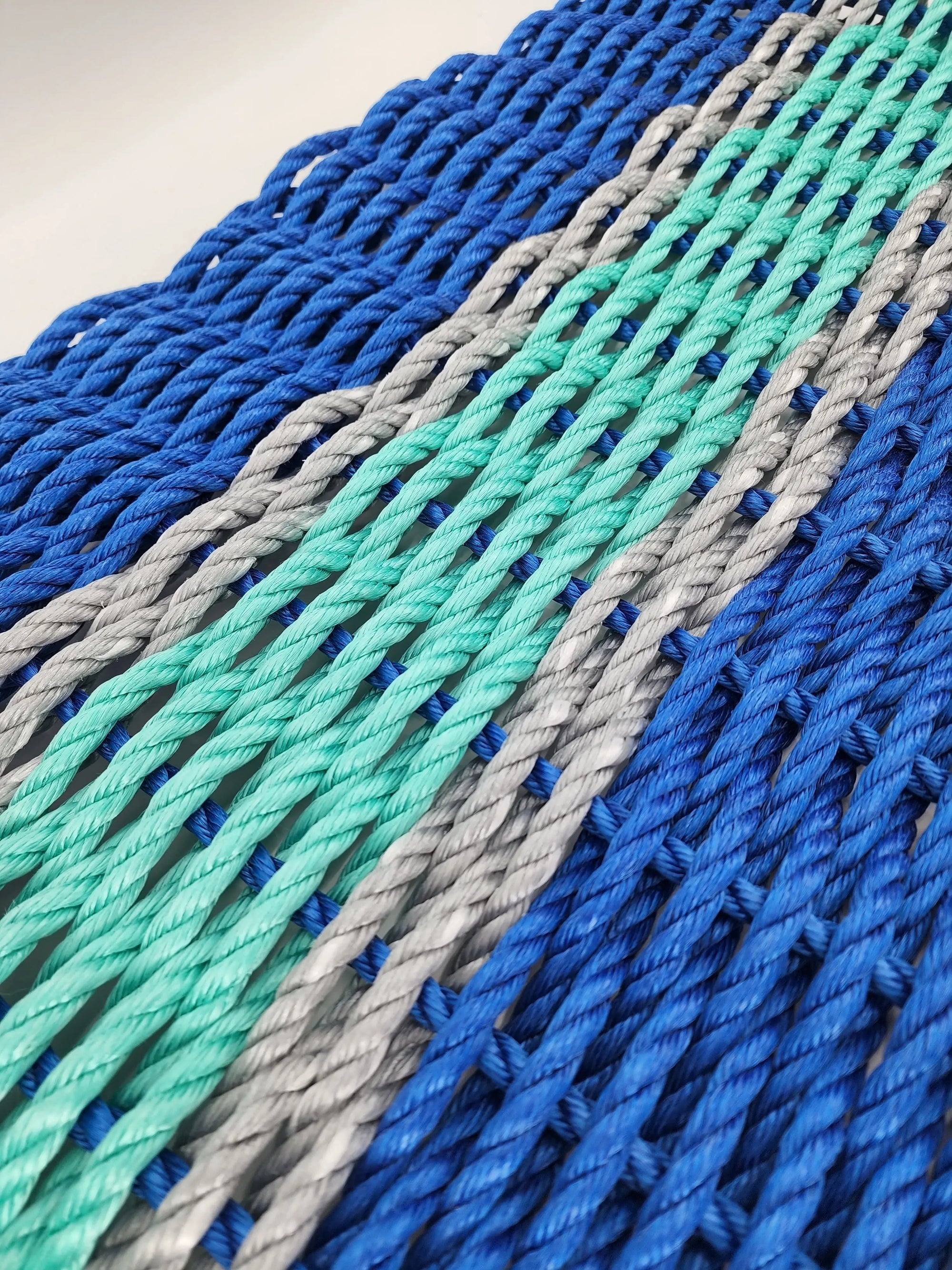 Handmade lobster rope door mat in blue, teal, and light gray accents