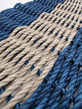 Handmade navy blue and tan lobster rope mat on wooden floor