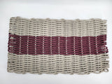 Handmade lobster rope mat in tan and burgundy colors on a wooden floor