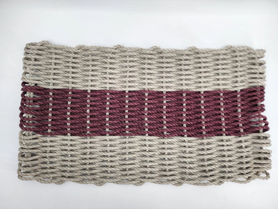 Handmade lobster rope mat in tan and burgundy colors on a wooden floor