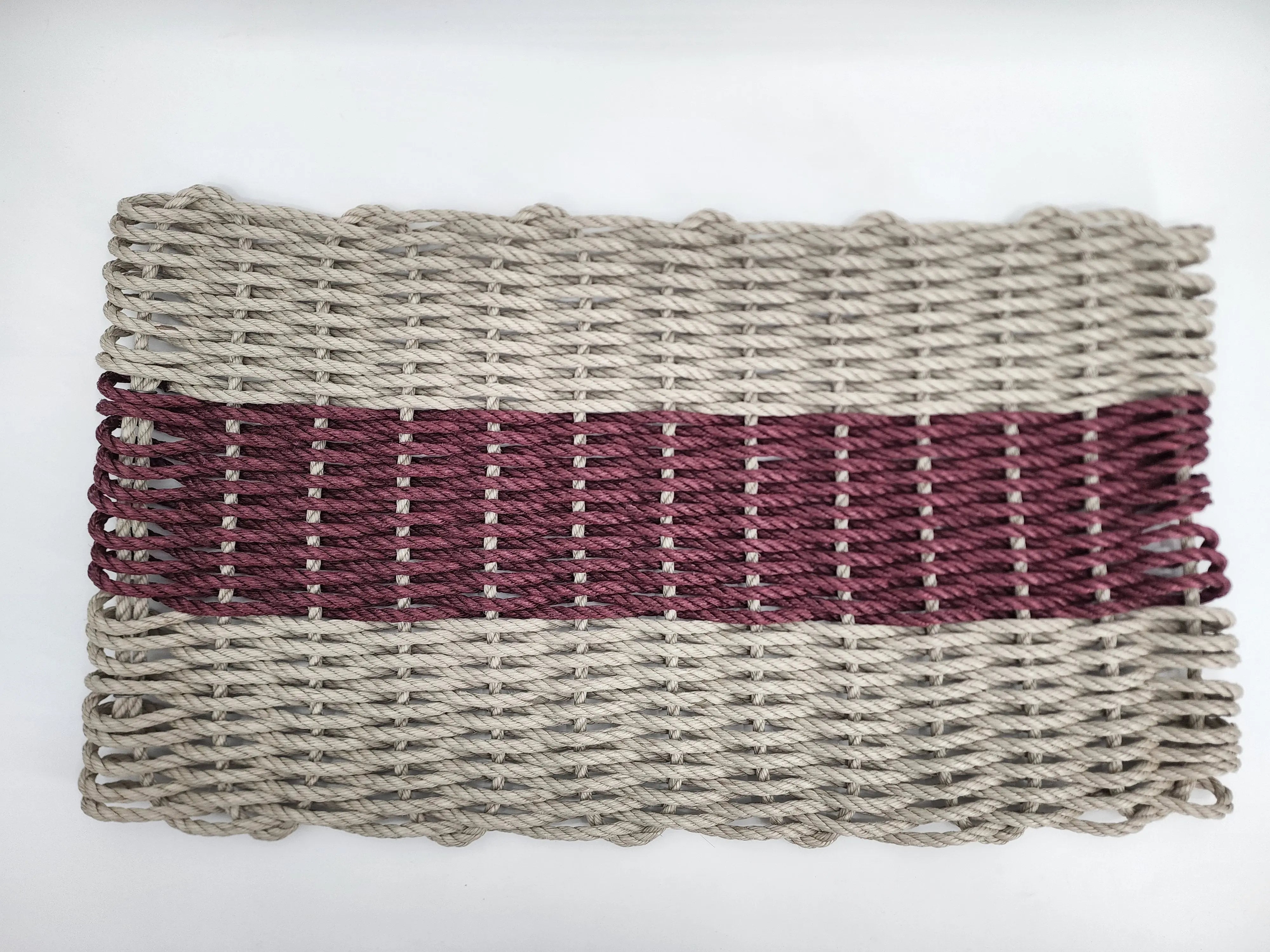 Handmade lobster rope mat in tan and burgundy colors on a wooden floor