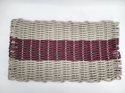 Handmade lobster rope mat in tan and burgundy colors on a wooden floor