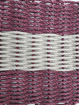 Burgundy and tan handmade lobster rope mat on wooden floor