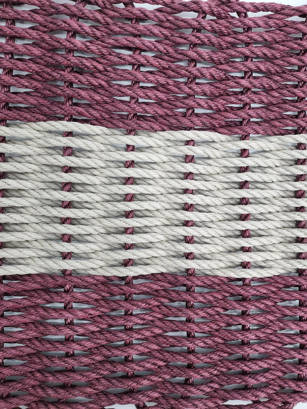 Burgundy and tan handmade lobster rope mat on wooden floor