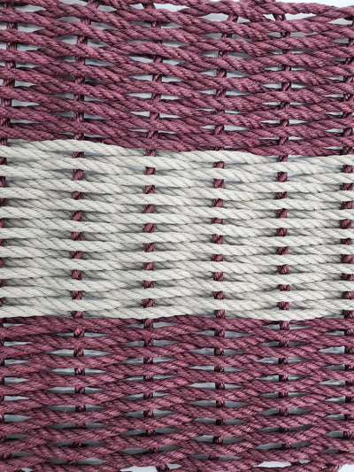Burgundy and tan handmade lobster rope mat on wooden floor