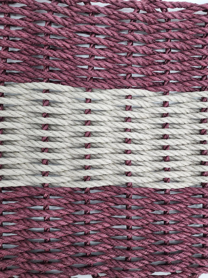 Burgundy and tan handmade lobster rope mat on wooden floor