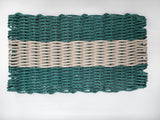 Hunter Green and Tan handmade lobster rope mat on wooden floor
