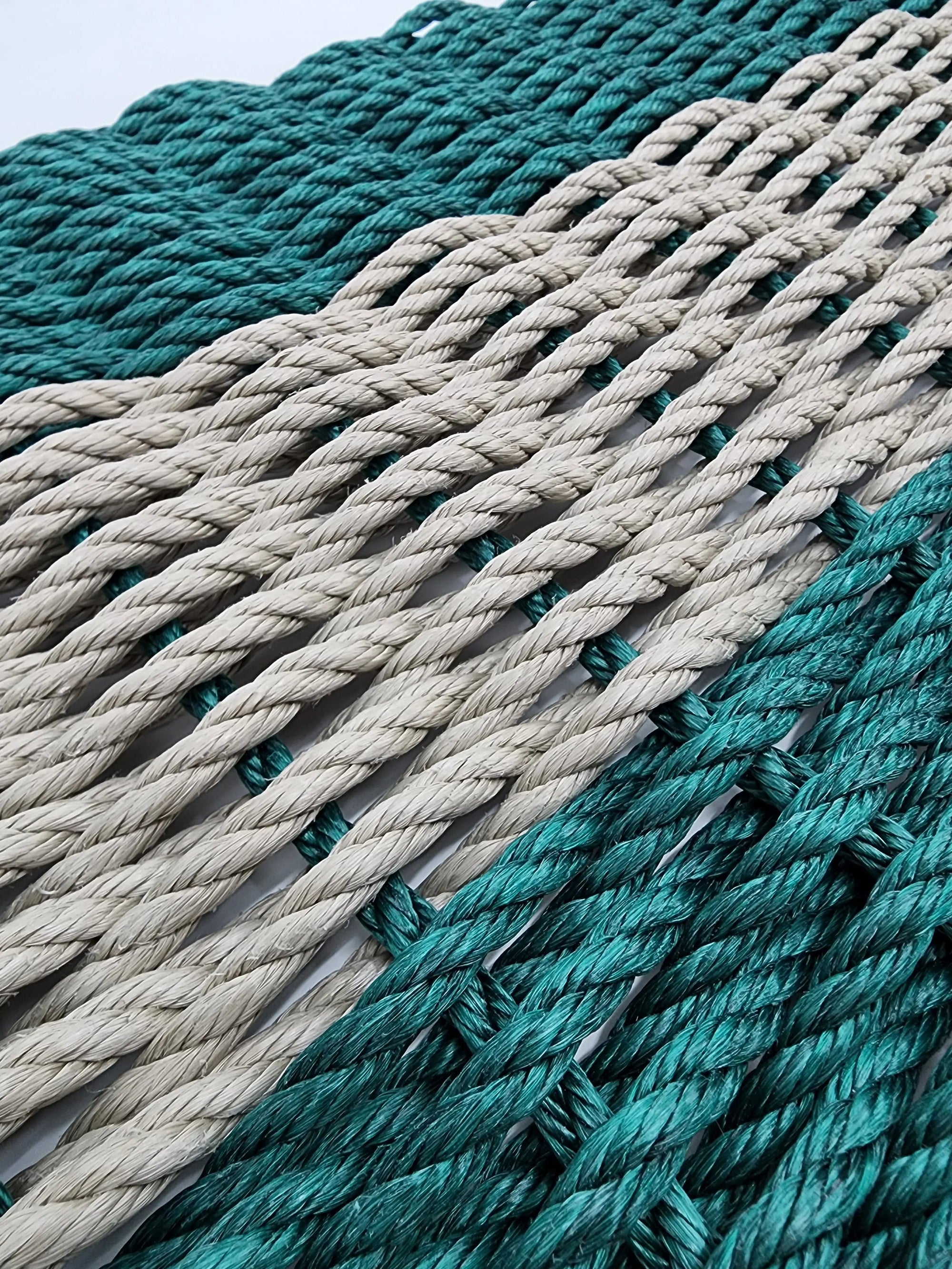 Hunter Green and Tan handmade lobster rope mat on wooden floor