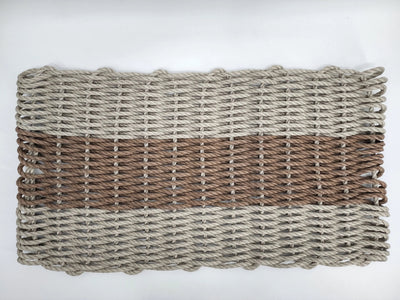Handmade lobster rope mat in tan and brown colors, displayed on wooden floor