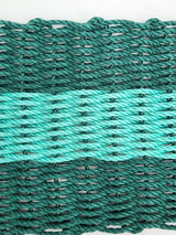 Hunter green and teal handmade lobster rope mat on wooden floor