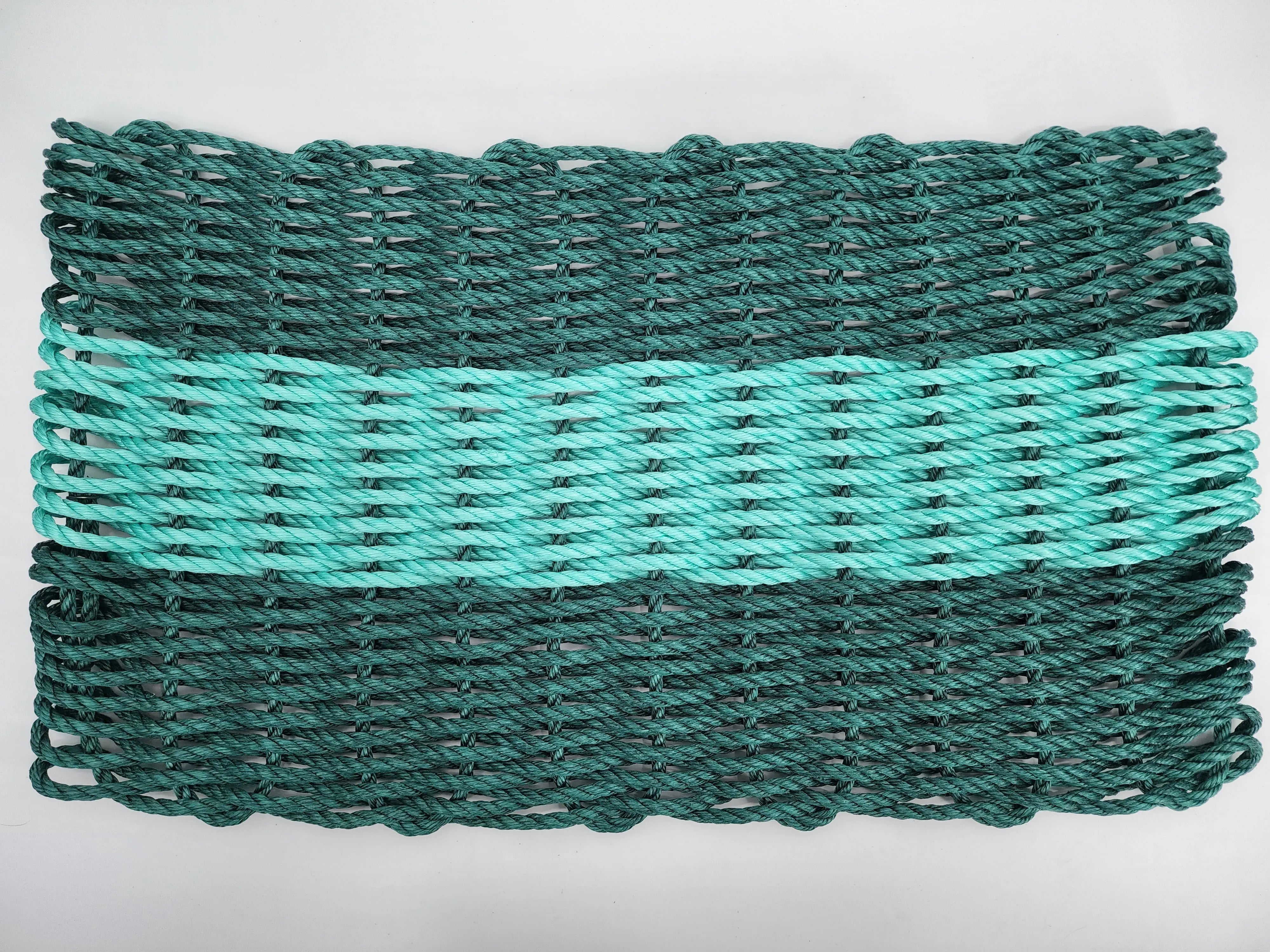 Hunter green and teal handmade lobster rope mat on wooden floor