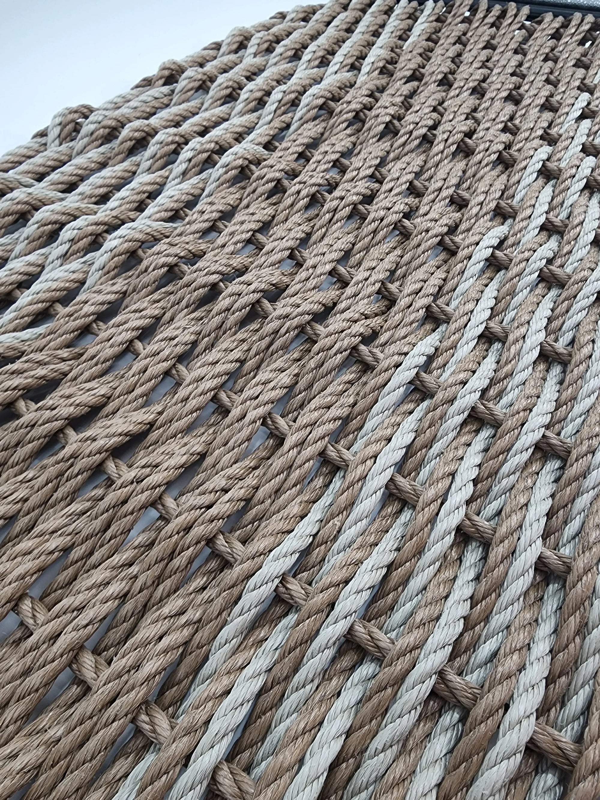Large brown and tan double weave lobster rope mat on wooden porch