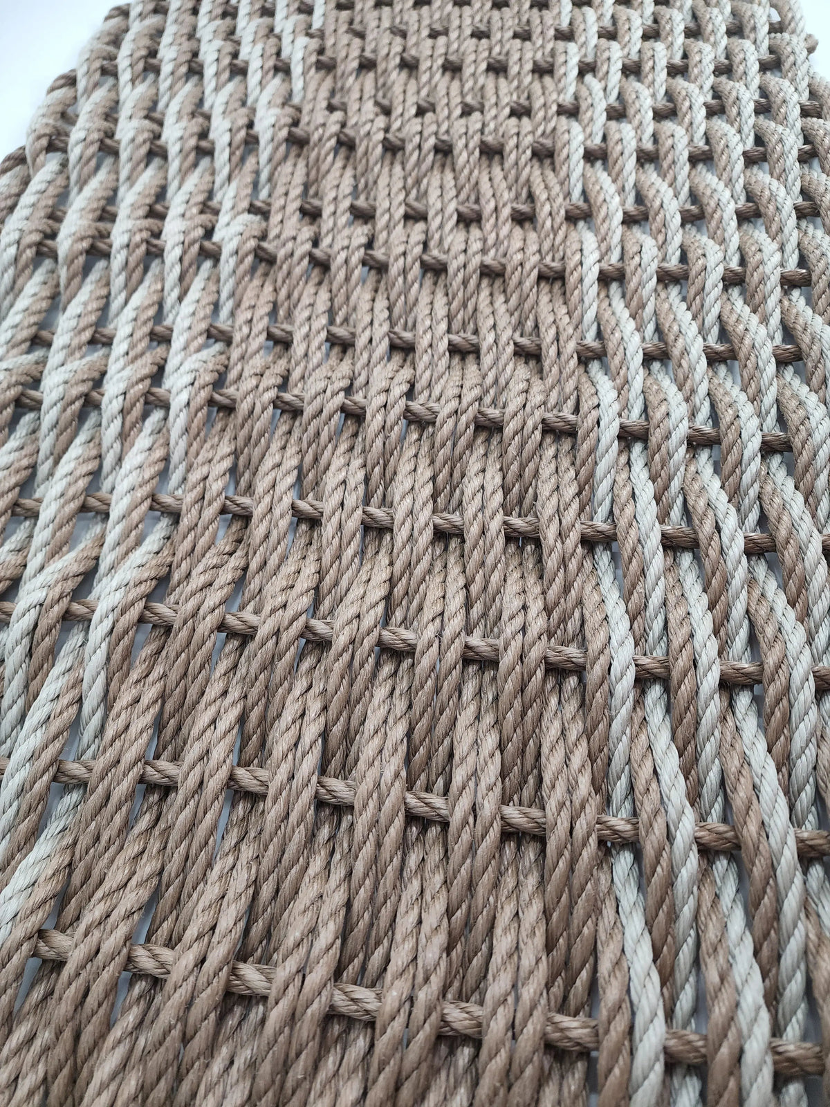 Large brown and tan double weave lobster rope mat on wooden porch
