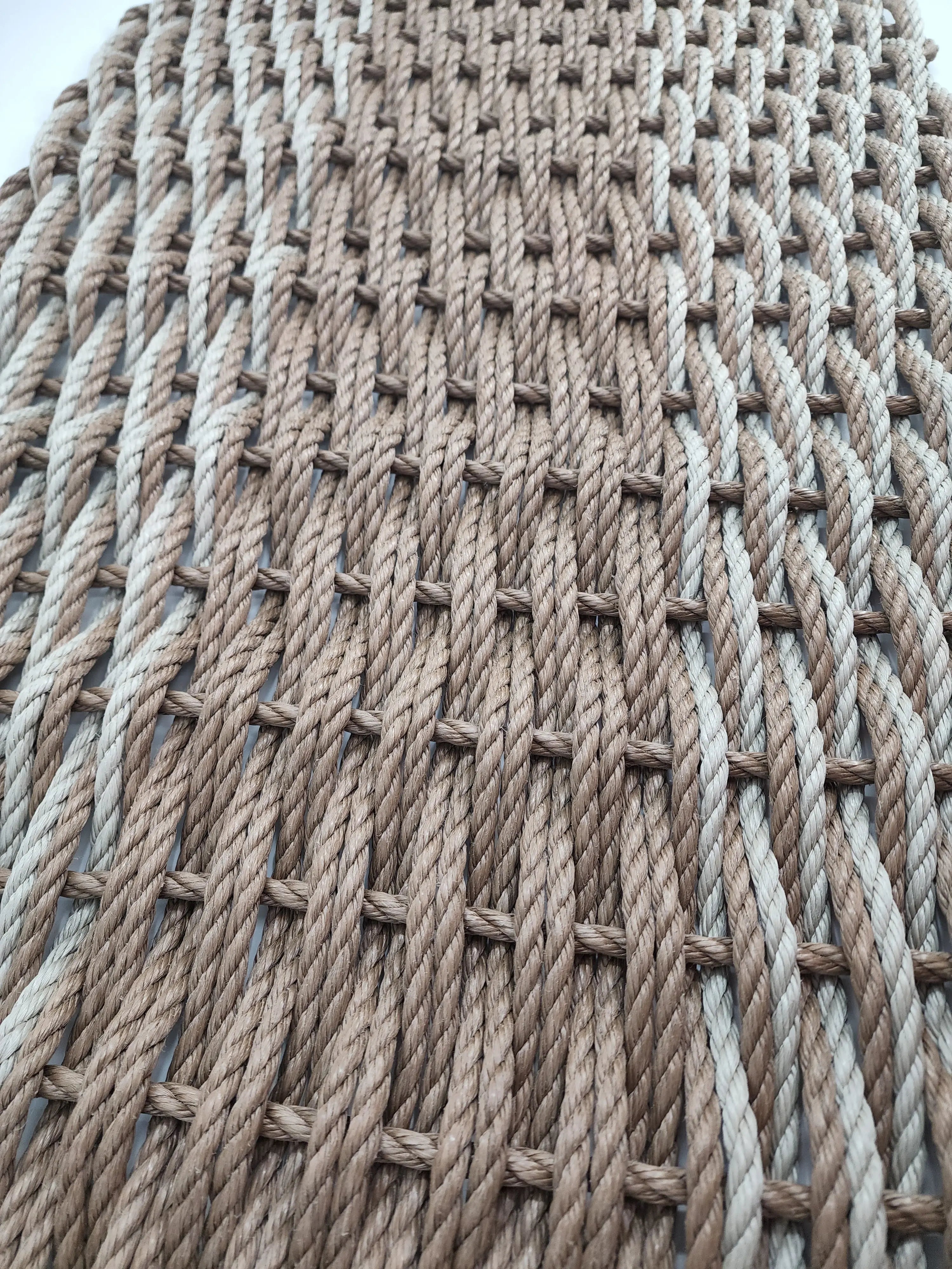 Large brown and tan double weave lobster rope mat on wooden porch